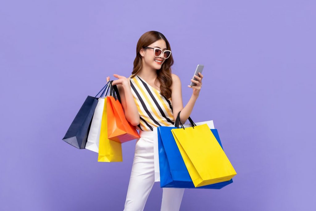 beautiful-asian-woman-carrying-colorful-bags-shopping-online-with-mobile-phone