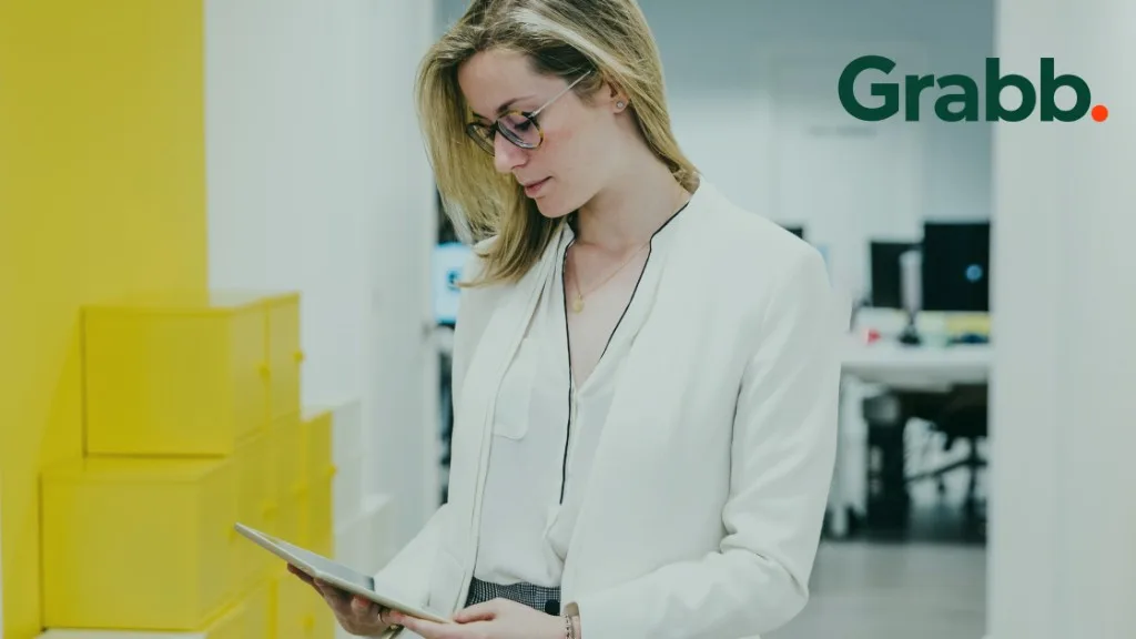 Professionnelle des ventes consultant des données de comptes et de commandes sur une tablette dans un bureau moderne