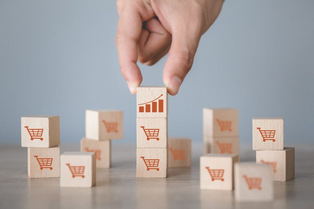 hand-arranging-wood-block-stacking-with-icon-graph-shopping-cart-symbol-upward-direction