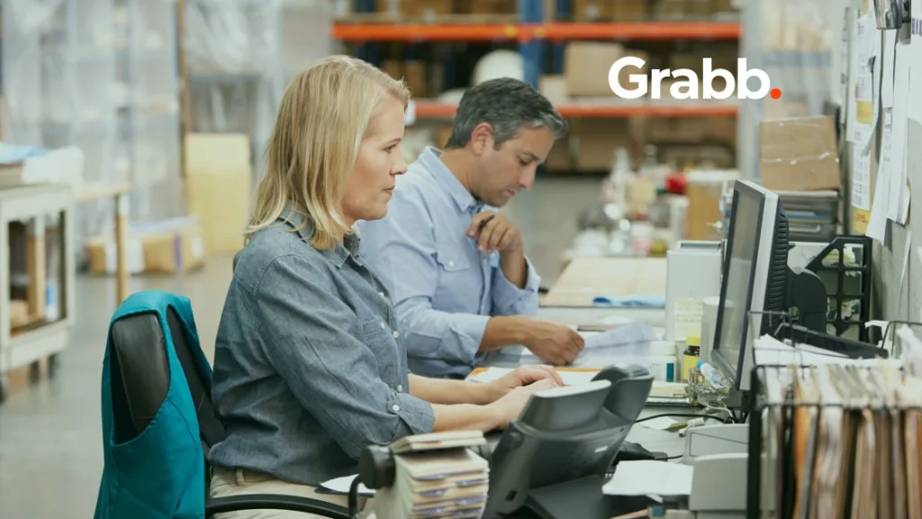 Order desk team reviewing documents and entering purchase orders in a warehouse office